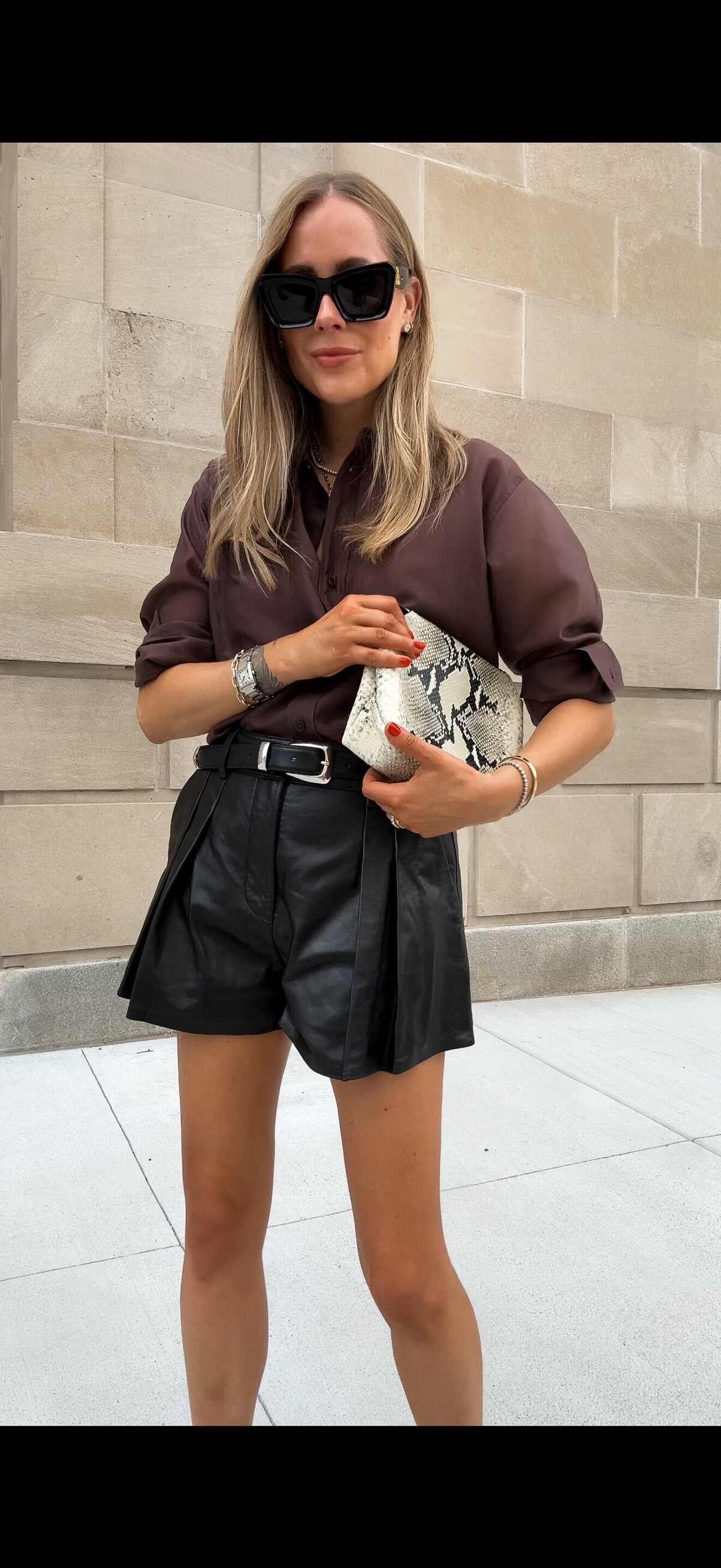 Brown knitwear and black shorts with a dark handbag
